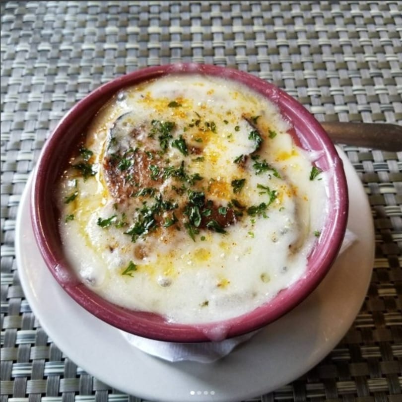 Elmwood Inn's French onion soup in a red crock with melted cheese and parsley.
